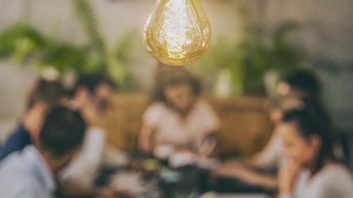 People seated at a table with a lightbulb in the forefront