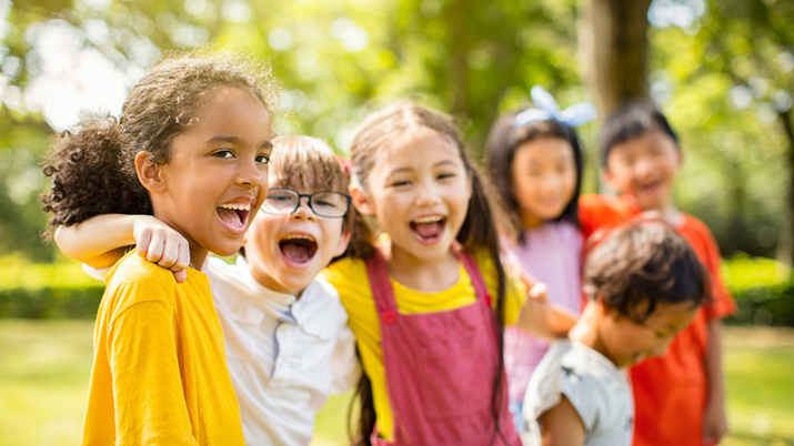 Photo description: Group of school children laughing and embracing