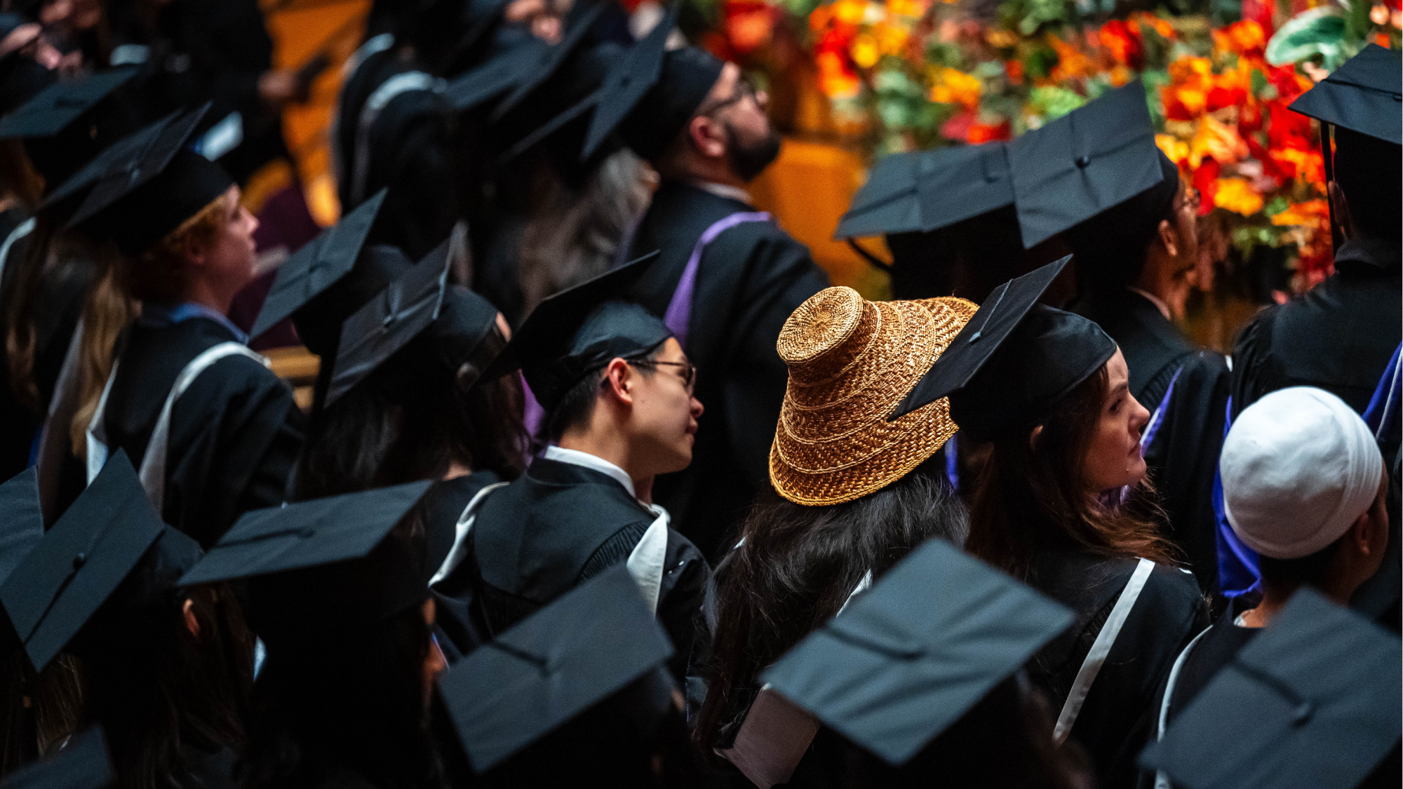 Graduates wearing caps and gowns seated at a UBC ceremony.